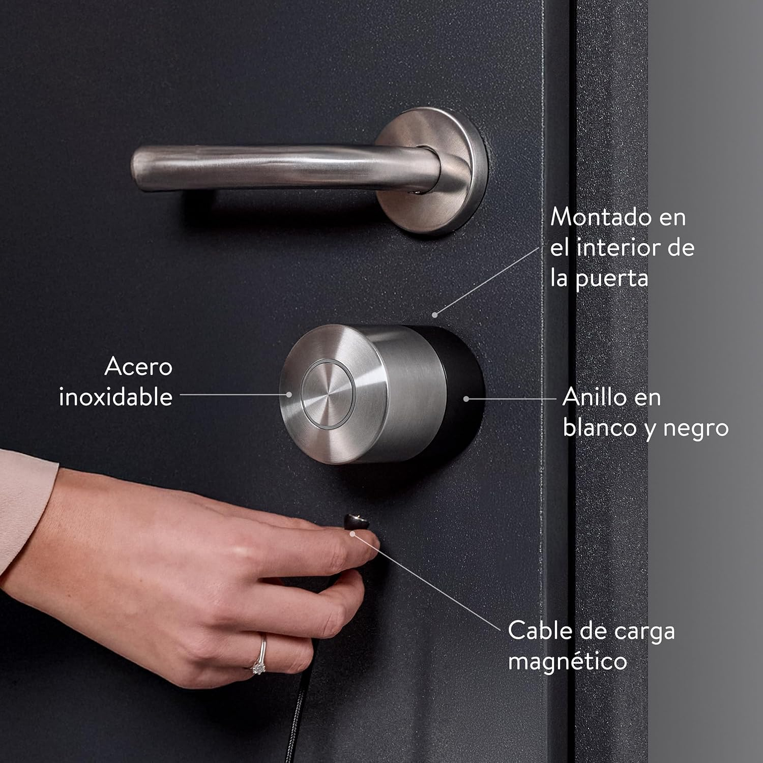 Cerradura inteligente instalada en una puerta negra. Mano sosteniendo cable de carga. Texto: "Acero inoxidable, anillo negro."
