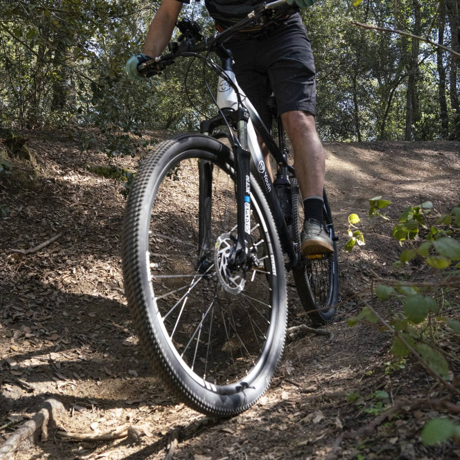 Persona montada en bicicleta de montaña en sendero de tierra en bosque.