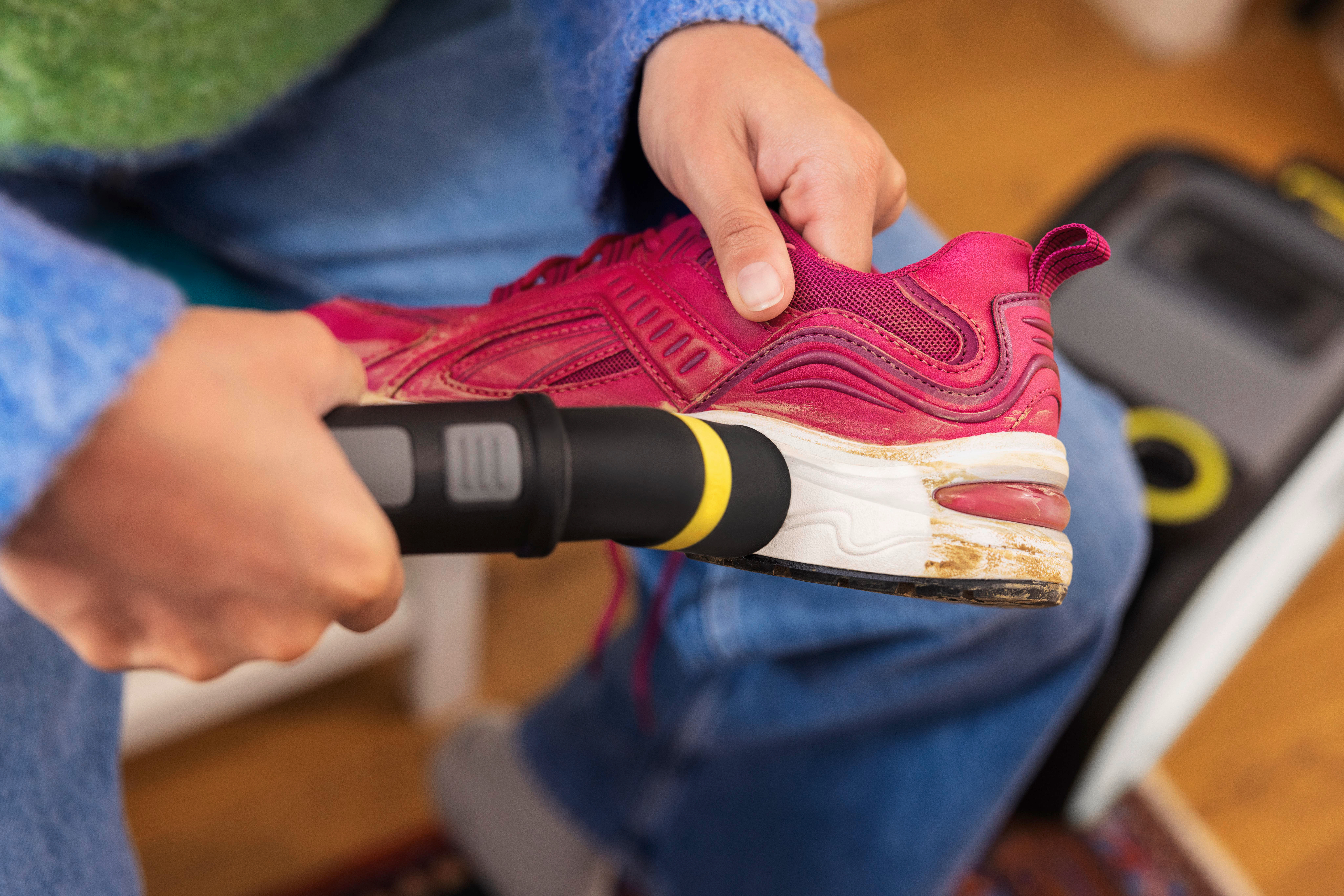 Eine Person reinigt einen roten Schuh mit einem Reinigungswerkzeug.