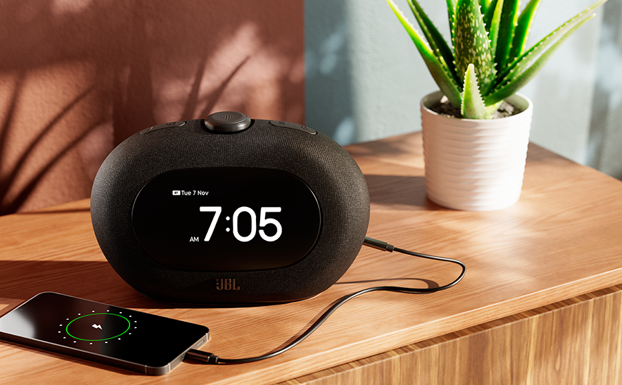 Radio-réveil JBL Horizon 3 affichant 7h05, chargeant un téléphone, avec une plante d'aloe.