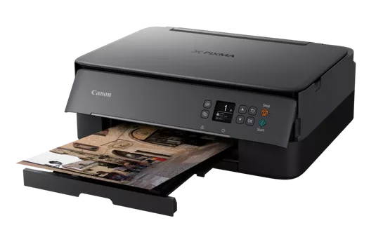Drukarka Canon Pixma drukująca zdjęcie. Drukarka jest pod kątem. Tło jest czarne.
