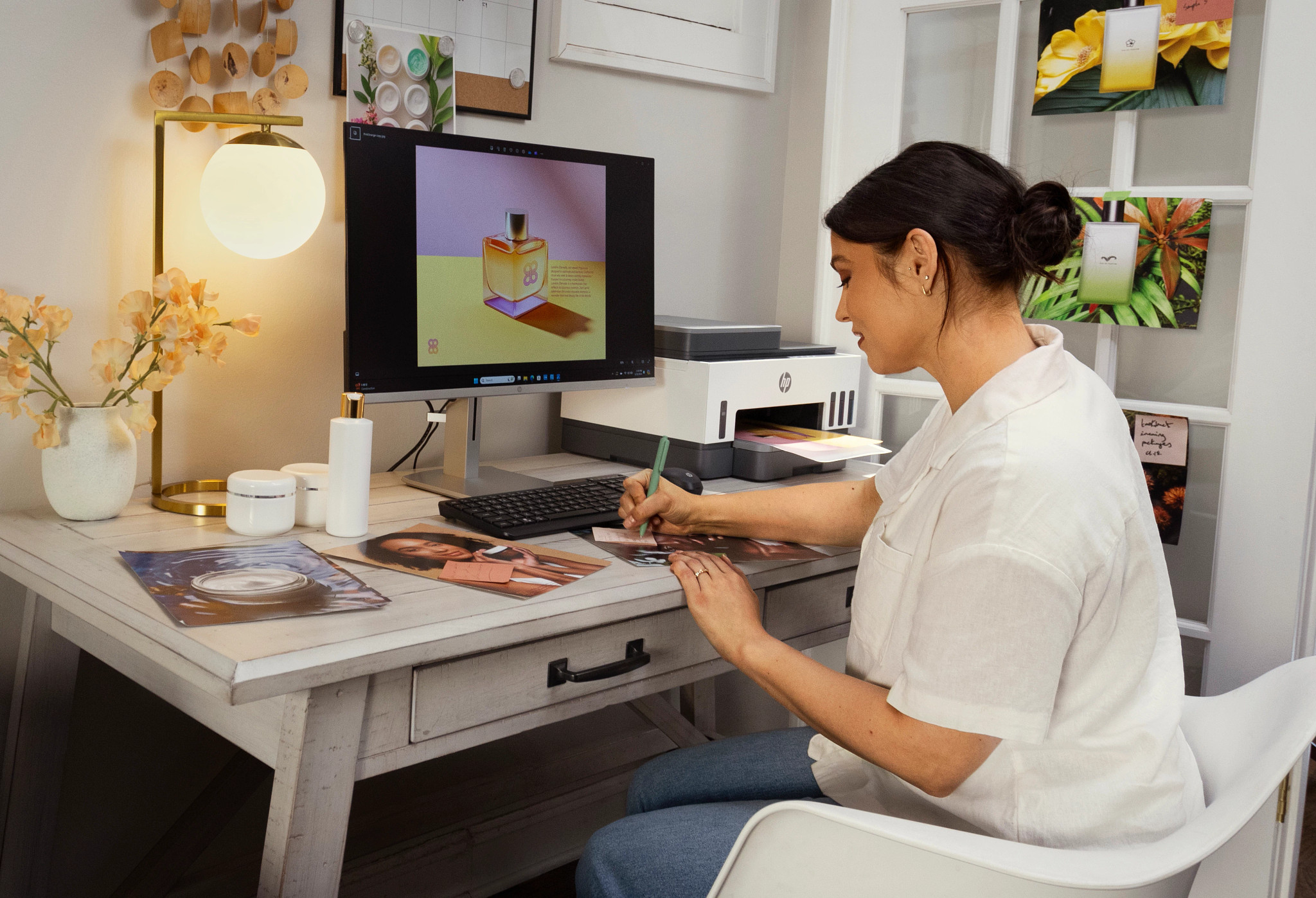 Eine Frau arbeitet an einem Schreibtisch mit Computer und HP-Drucker und überprüft gedruckte Fotos.