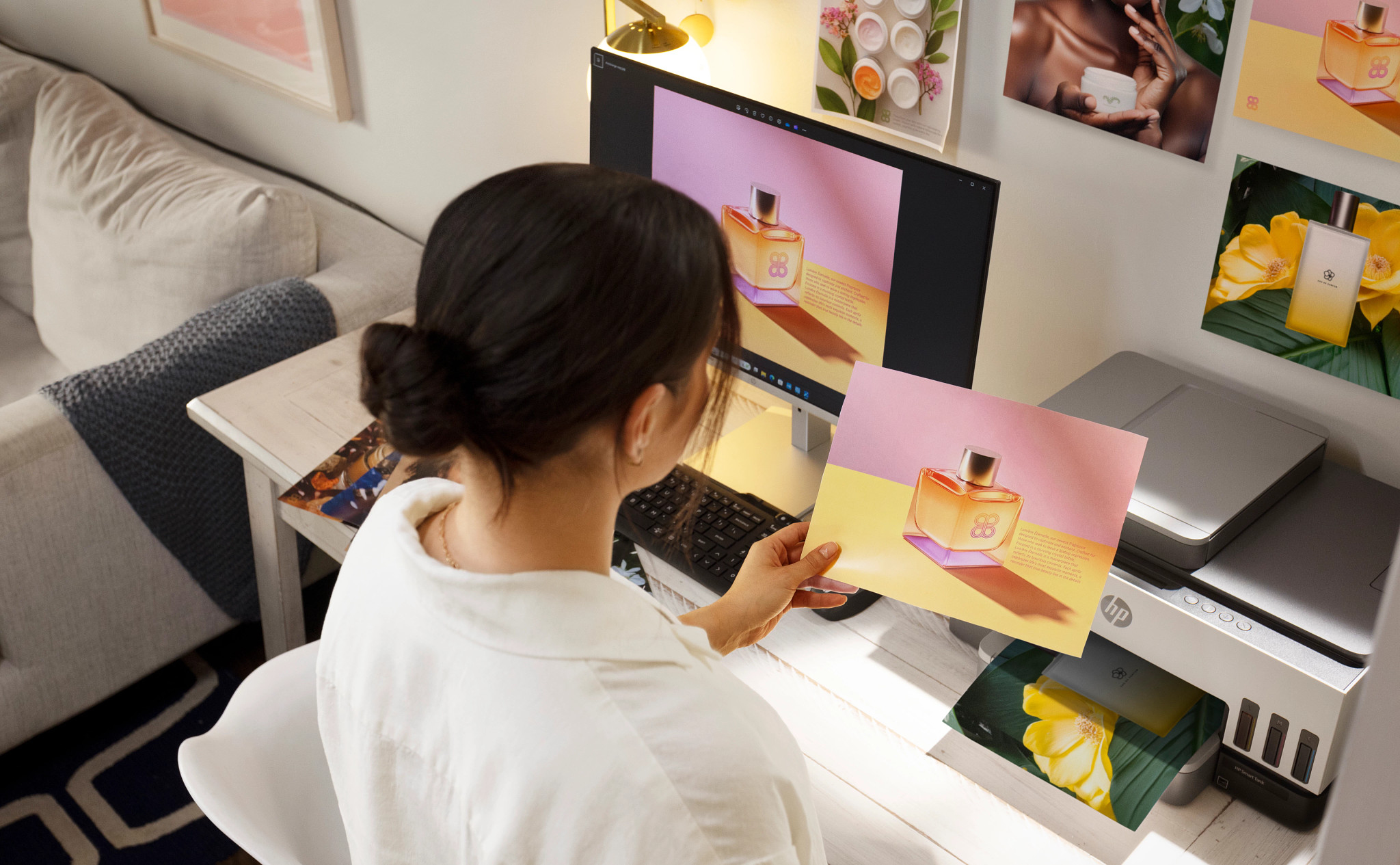 Frau arbeitet am Computer, Drucker druckt Fotos. Fotos von Parfüm.
