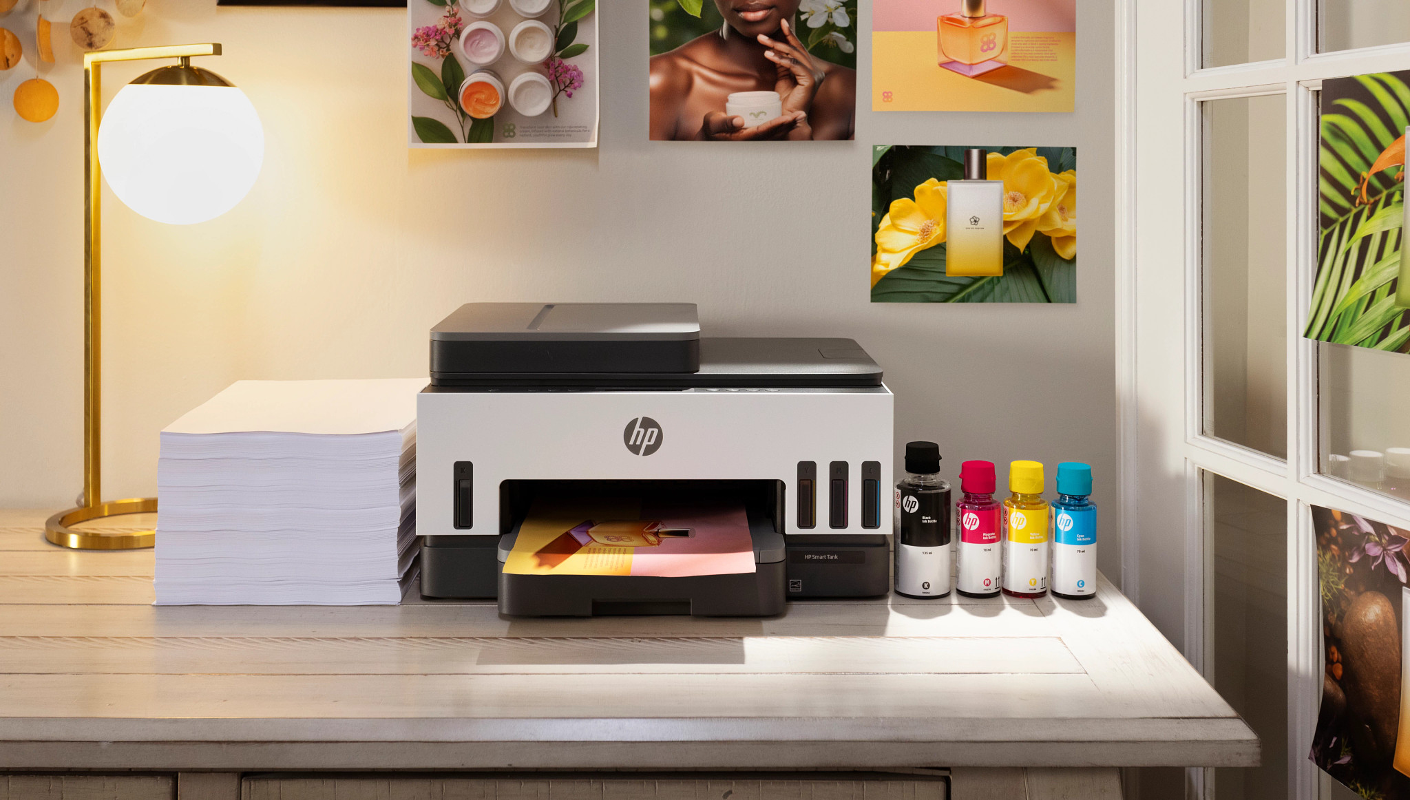 Drucker druckt Fotos. Tintenflaschen und Papierstapel auf dem Schreibtisch.