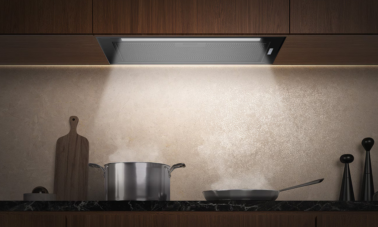 Kuchnia z okapem nad garnkiem i patelnią. Okap jest podświetlony, a światło świeci w dół.