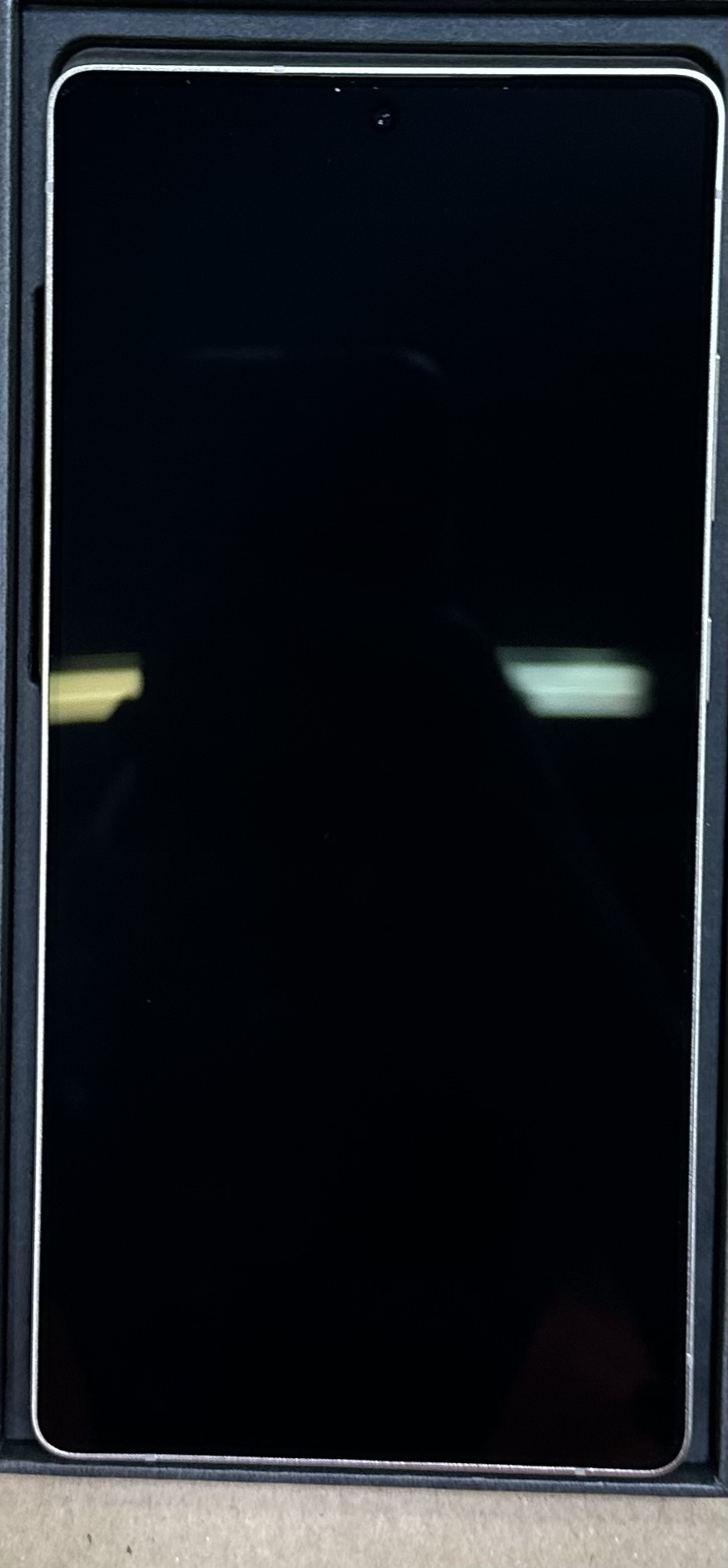 Tablet w czarnym pudełku. Ekran jest czarny, z aparatem u góry pośrodku.
