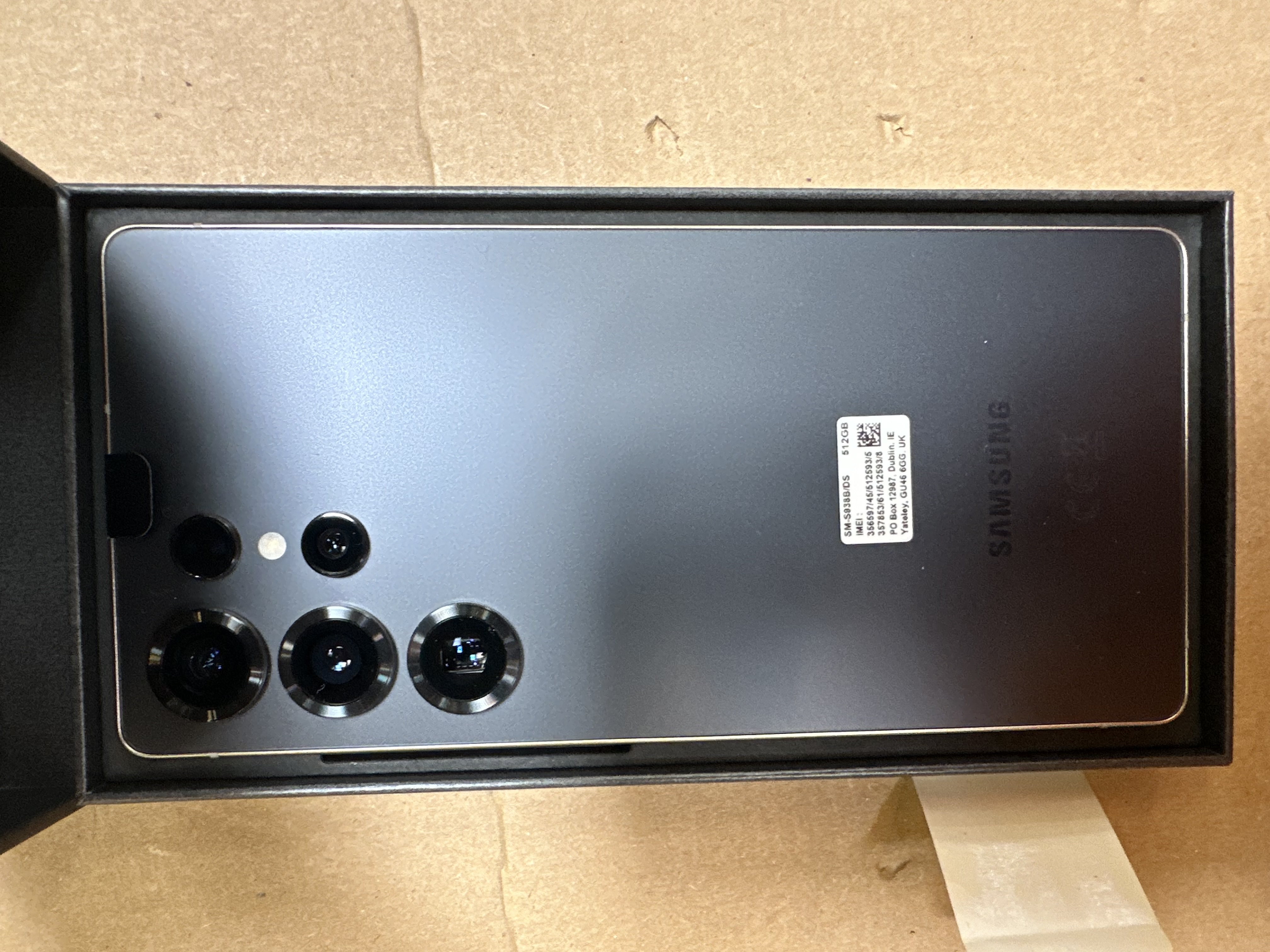 Telefon Samsung w czarnym pudełku. Tył telefonu ma wiele aparatów. Widoczna etykieta.