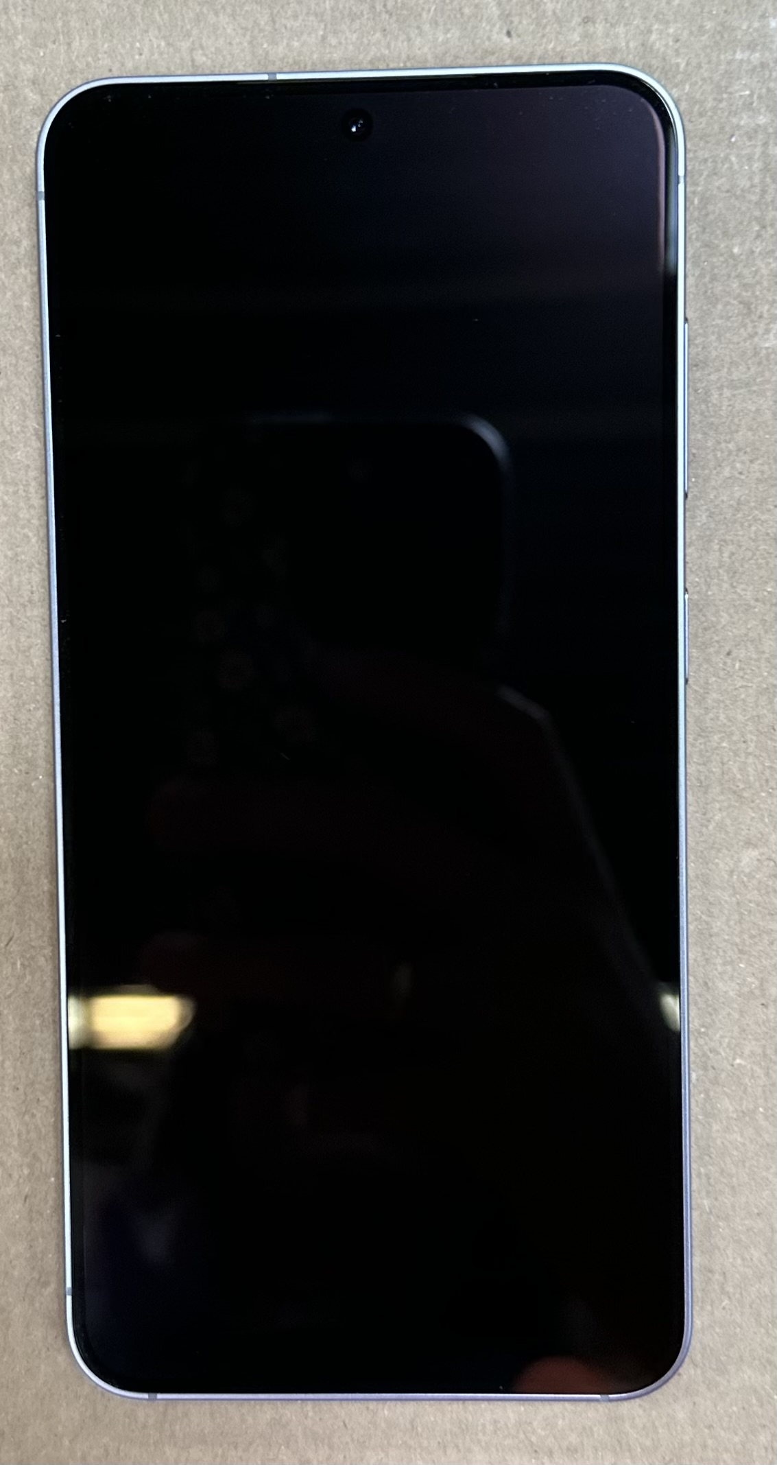 Telefon z czarnym ekranem, telefon jest srebrny z przednim aparatem.