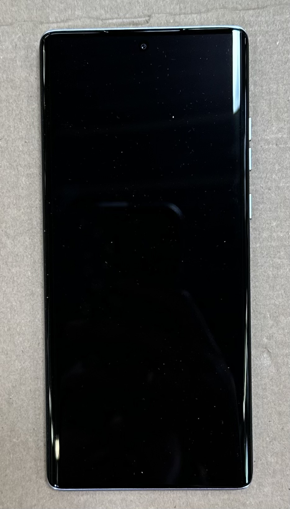 Czarny ekran telefonu z cienką ramką, telefon jest biały.