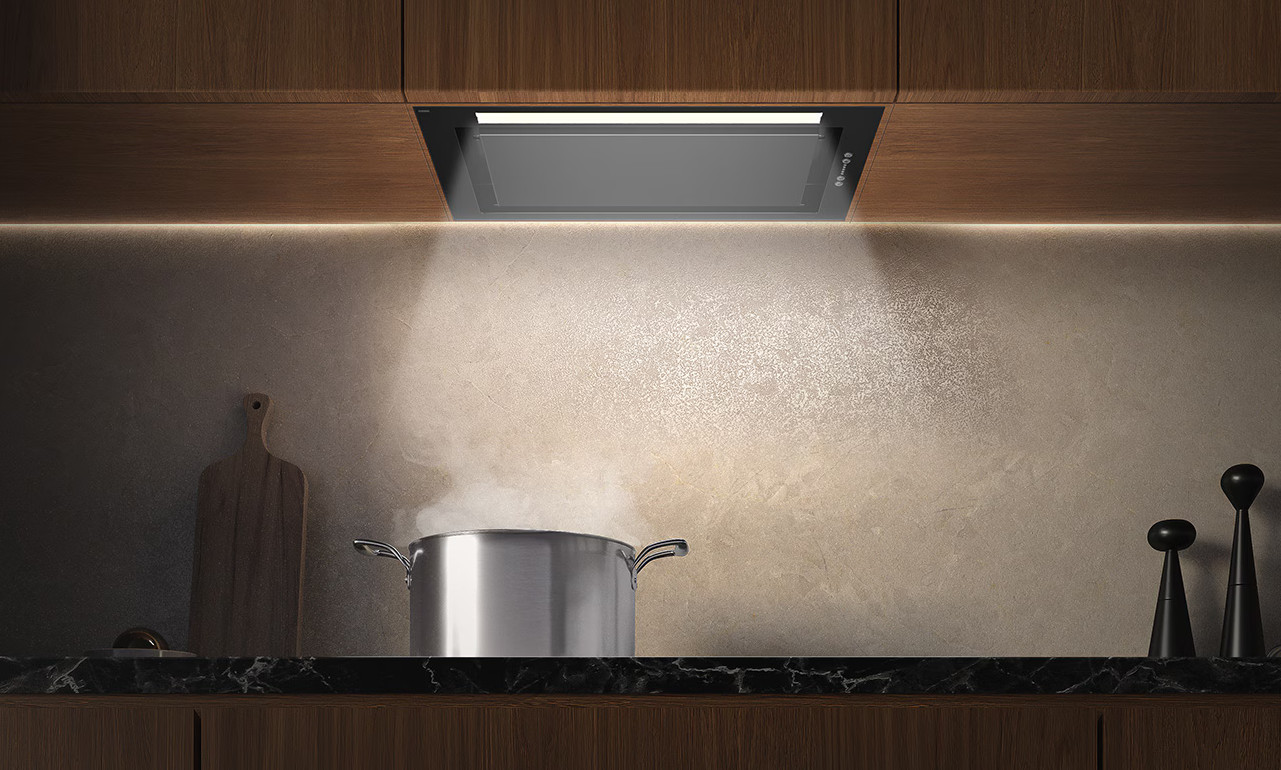 Czarny okap z oświetleniem nad garnkiem z parą unoszącą się w górę.