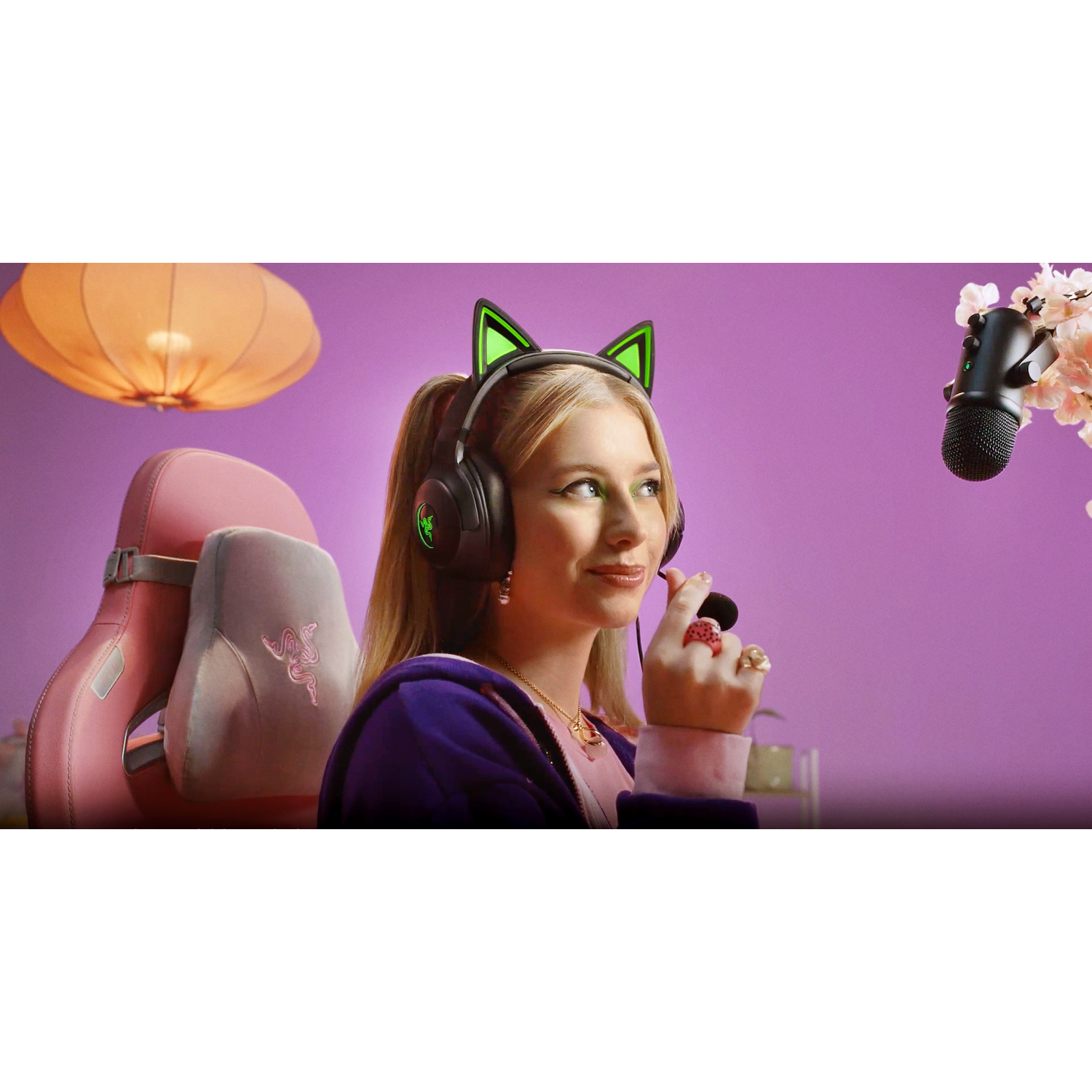 Blonde woman wearing a headset with cat ears, smiling, in a gaming setup.
