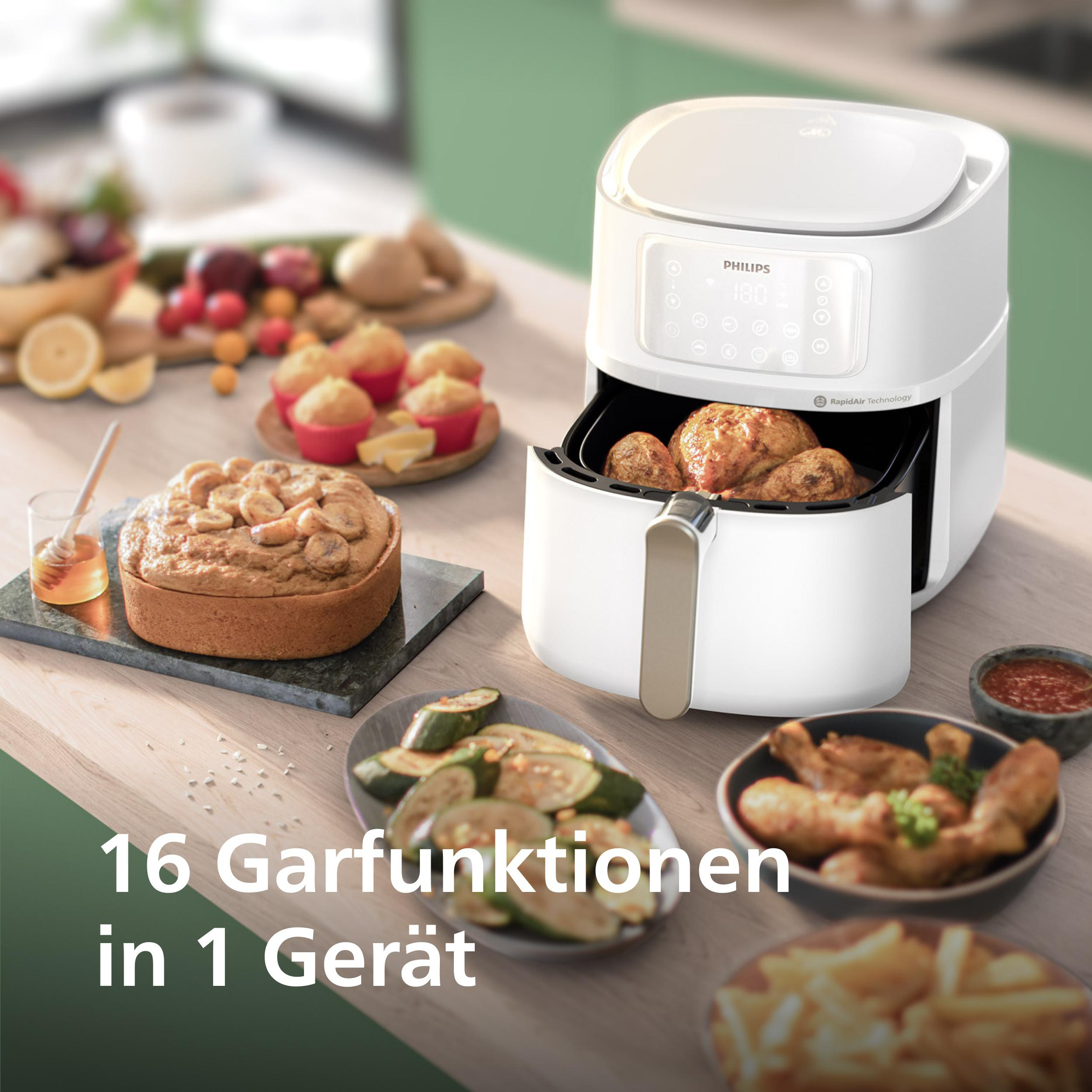Weißer Heißluftfritteuse mit verschiedenen Gerichten auf der Theke. Grüner Hintergrund.