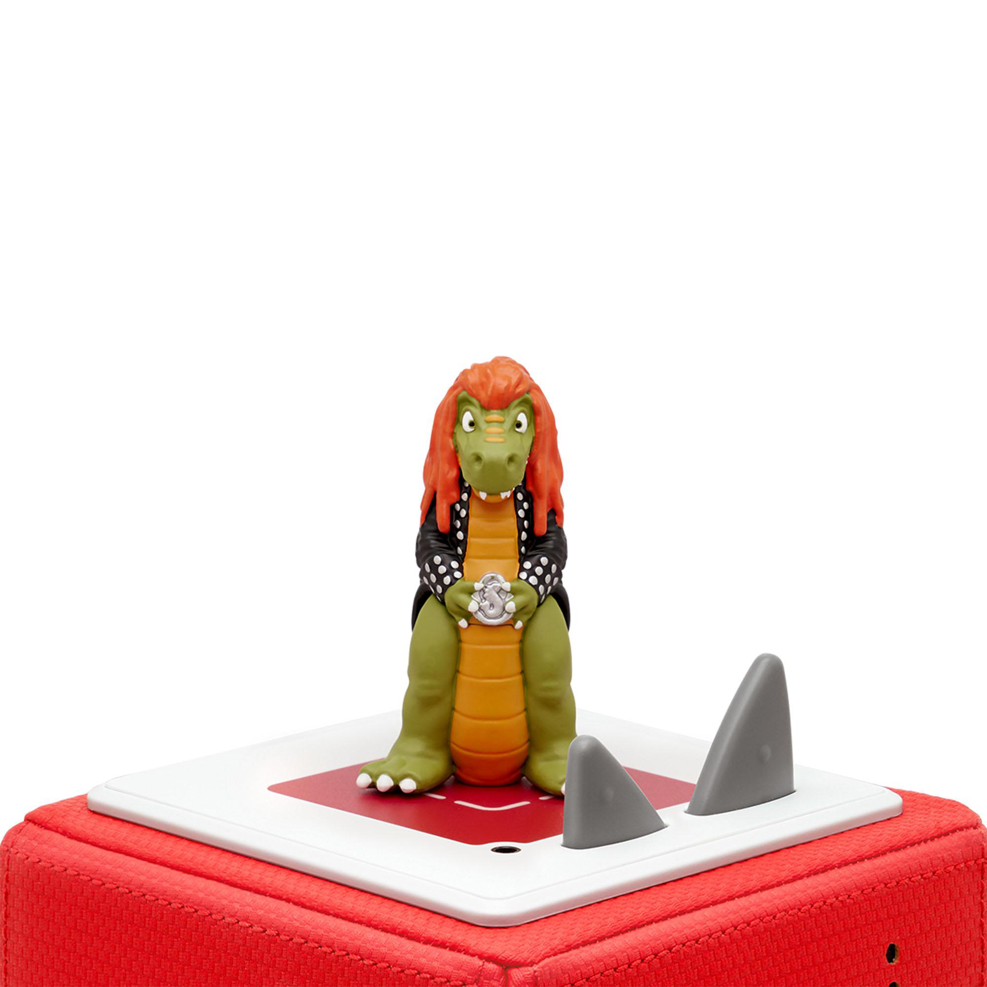 Eine Zeichentrick-Alligatorfigur mit Jacke, oben auf einem roten Würfel mit Haifischflossen.