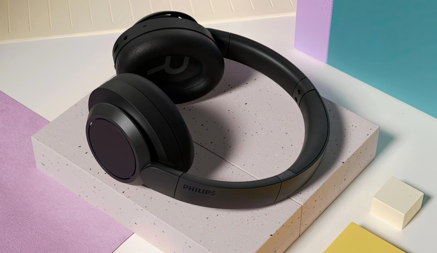 Czarne słuchawki w studiu. Niebieskie, różowe i żółte elementy w tle.