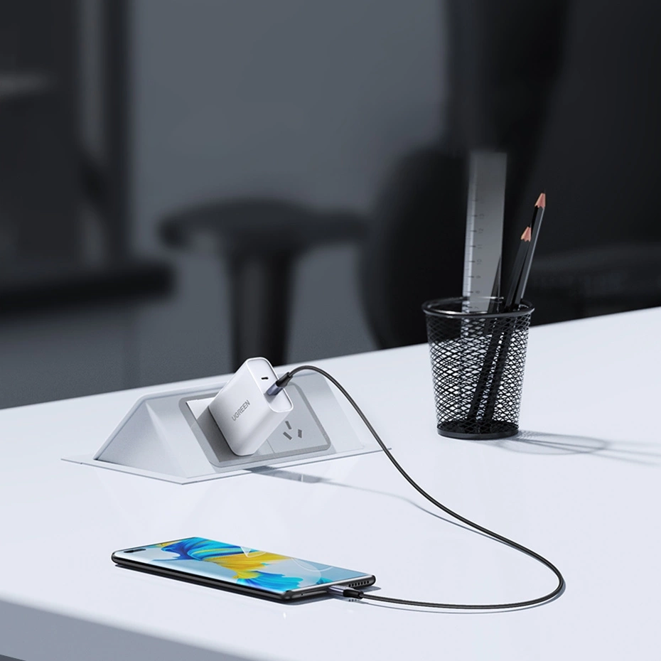 Bir telefon beyaz bir masada beyaz bir şarj cihazına bağlı.