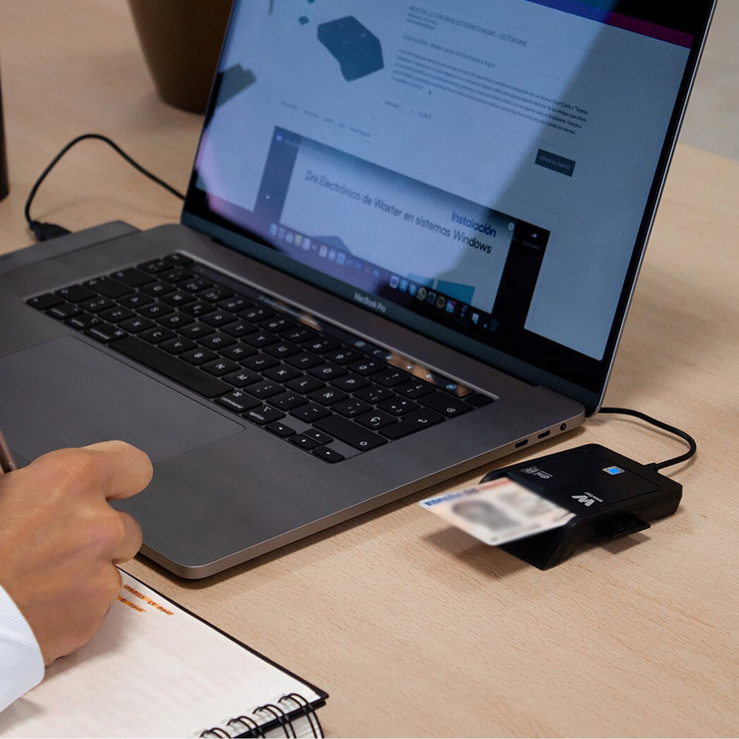 Hombre usando un portátil, con un lector de tarjetas DNI y una tarjeta insertada. Web en pantalla.
