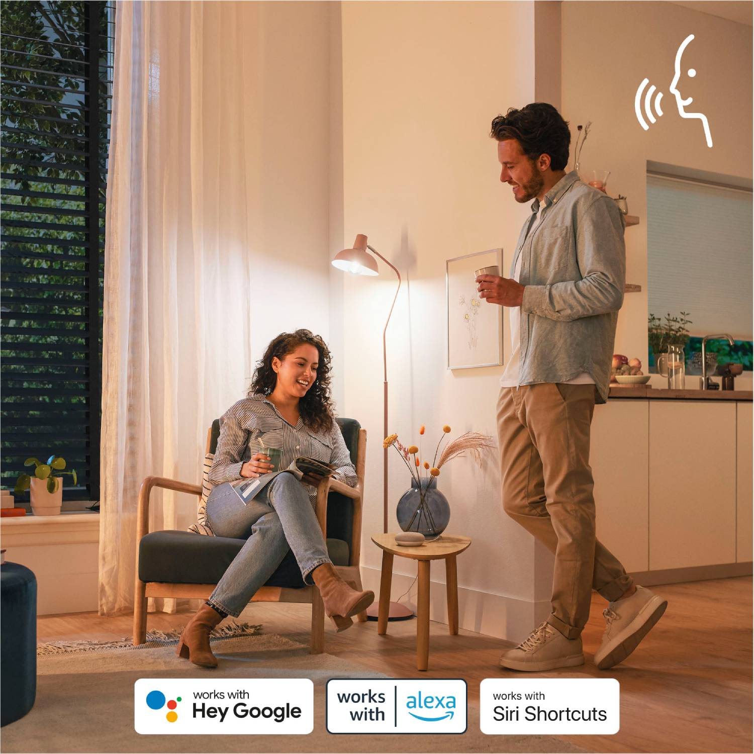 Dos personas en un salón, interactuando. Funciones de iluminación inteligente con iconos de control por voz.