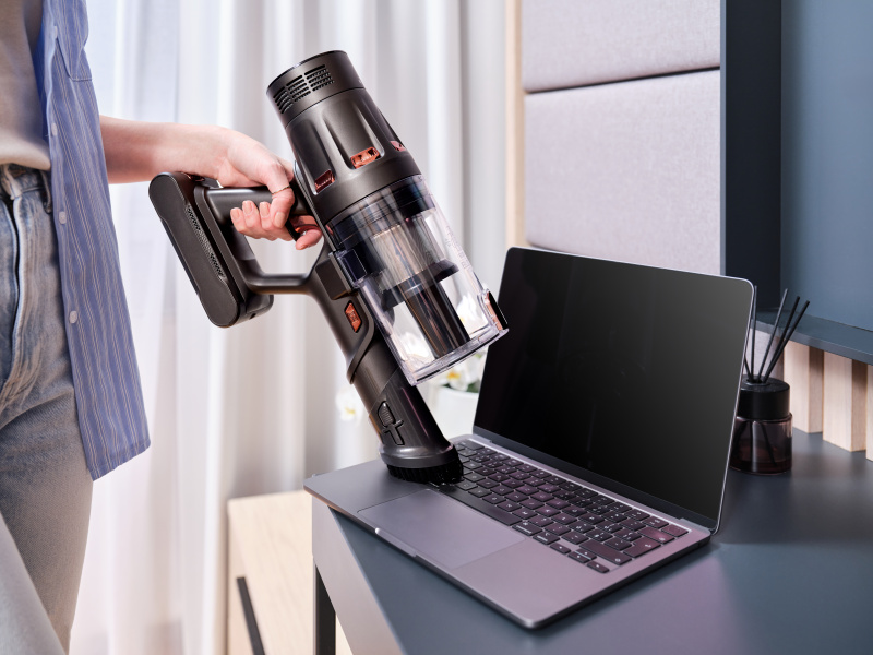 Egy személy fekete és réz porszívót használ a laptopon.