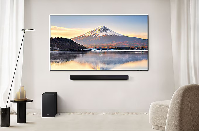 Salon z telewizorem na ścianie. Soundbar pod telewizorem, subwoofer na podłodze.