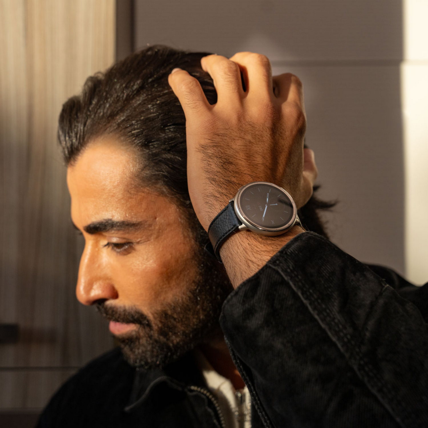 Hombre mirando hacia abajo, usando un smartwatch con una correa negra.
