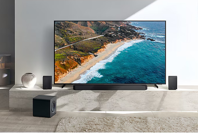 Salon z telewizorem, soundbarem, subwooferem i głośnikami. Pokój ma nowoczesny design.