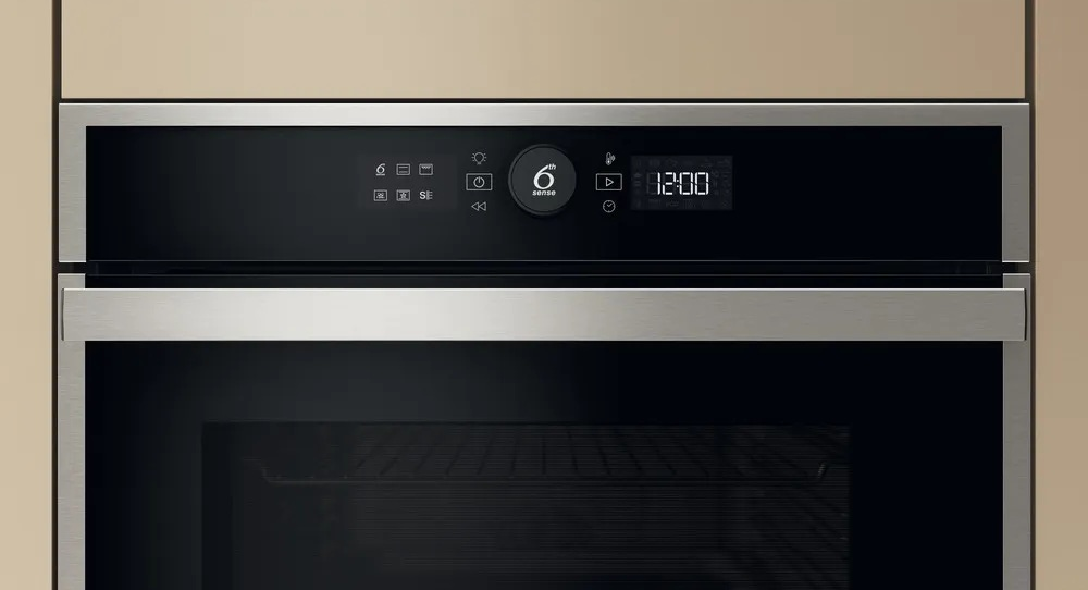 Zbliżenie panelu sterowania piekarnika z wyświetlaczem cyfrowym pokazującym 12:00 i różne ikony.