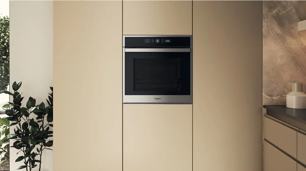 Piekarnik wbudowany w szafkę kuchenną. Piekarnik jest czarny i srebrny z wyświetlaczem cyfrowym.