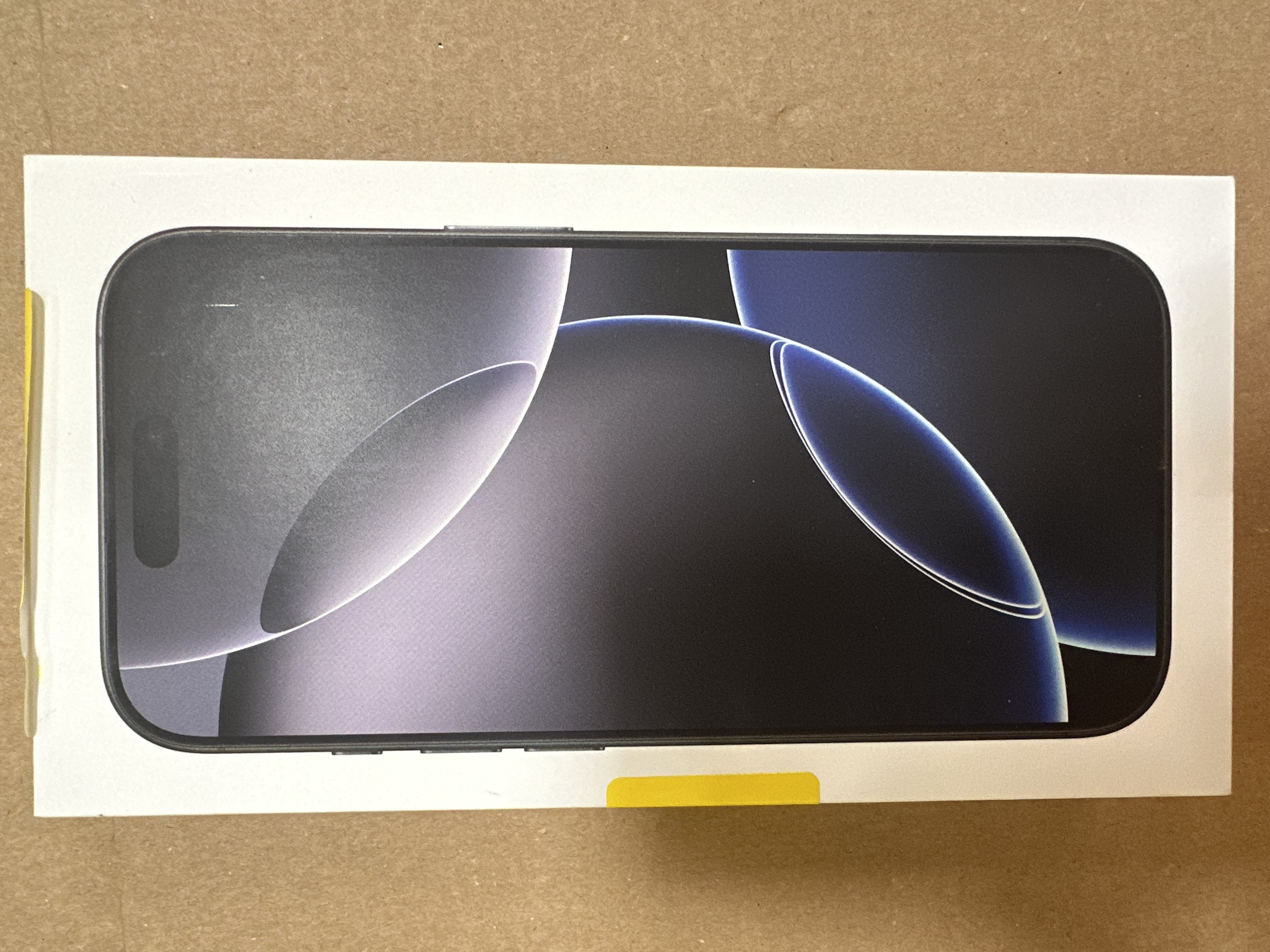 Zapakowany iPhone. Przód pudełka pokazuje obraz ekranu telefonu.