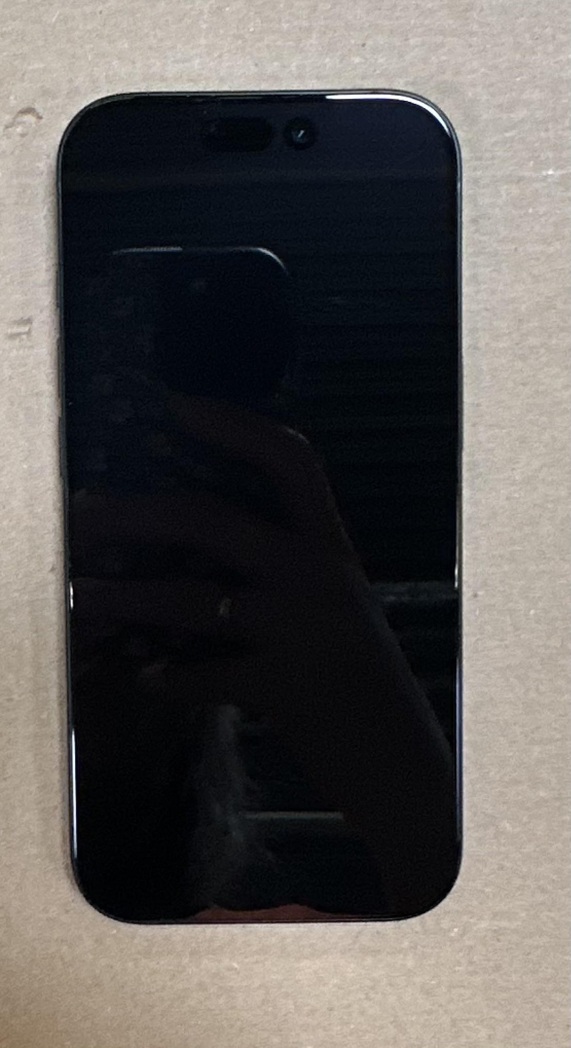 Czarny ekran iPhone'a. Ekran jest na beżowym tle.