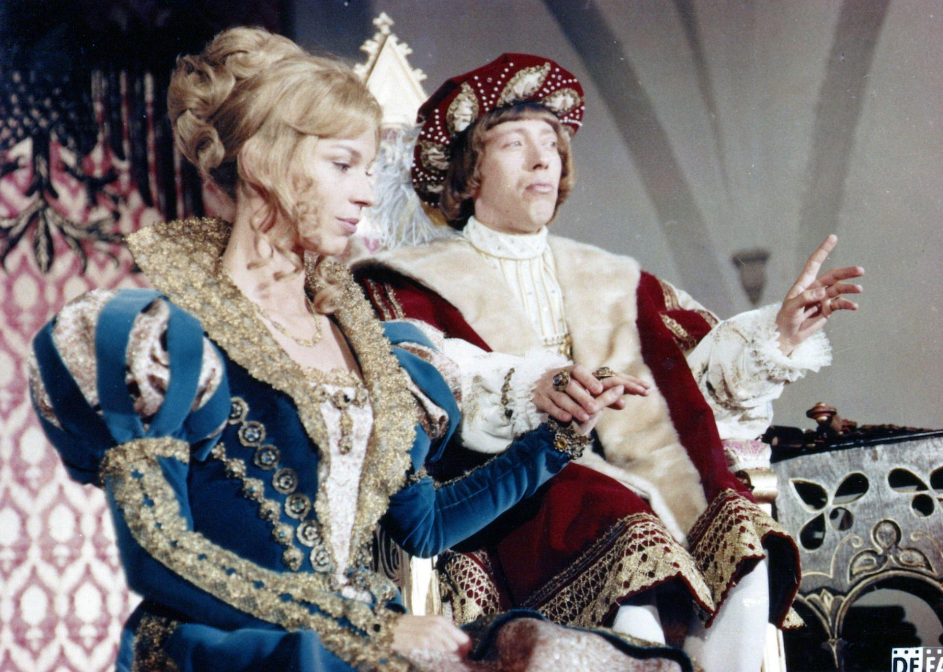 Zwei Personen in historischer Kleidung. Eine Frau in einem blauen Kleid und ein Mann in rotem Hut und Jacke.