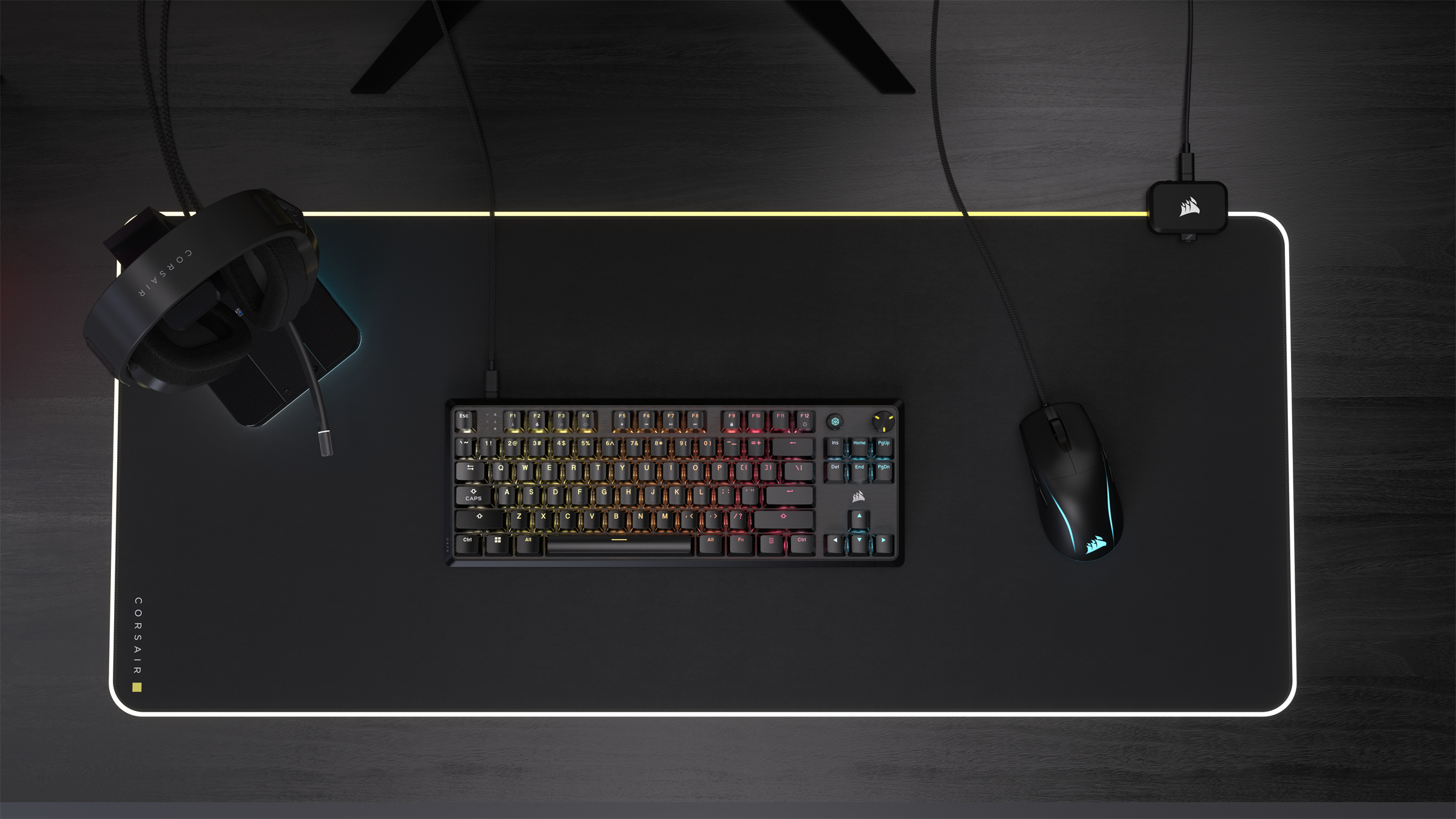 Ein Gaming-Setup mit Tastatur, Maus, Headset auf einem schwarzen Mauspad. Der Hintergrund ist dunkel.