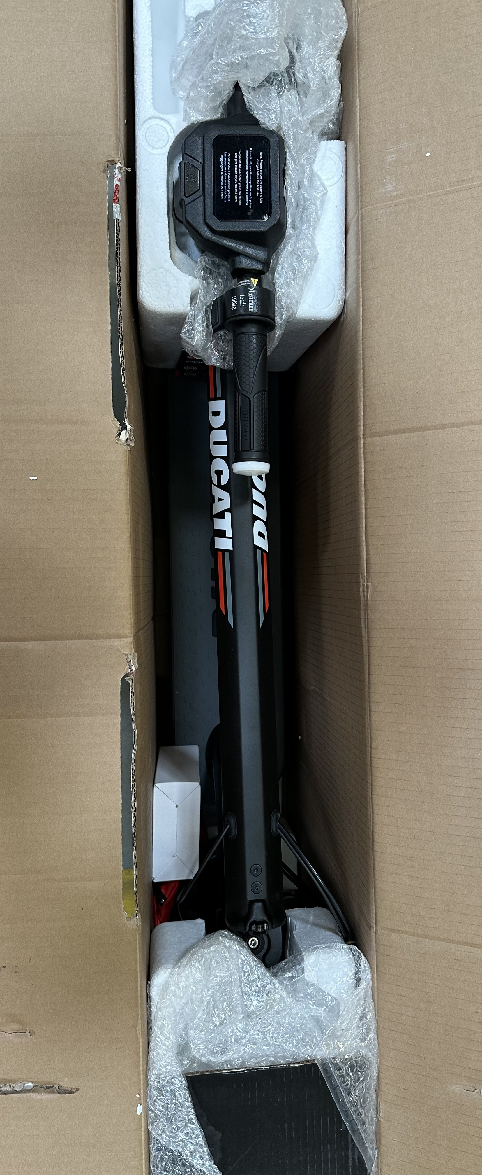 Hulajnoga elektryczna Ducati PRO-II w pudełku. Widok z góry. Czarno-czerwona hulajnoga.