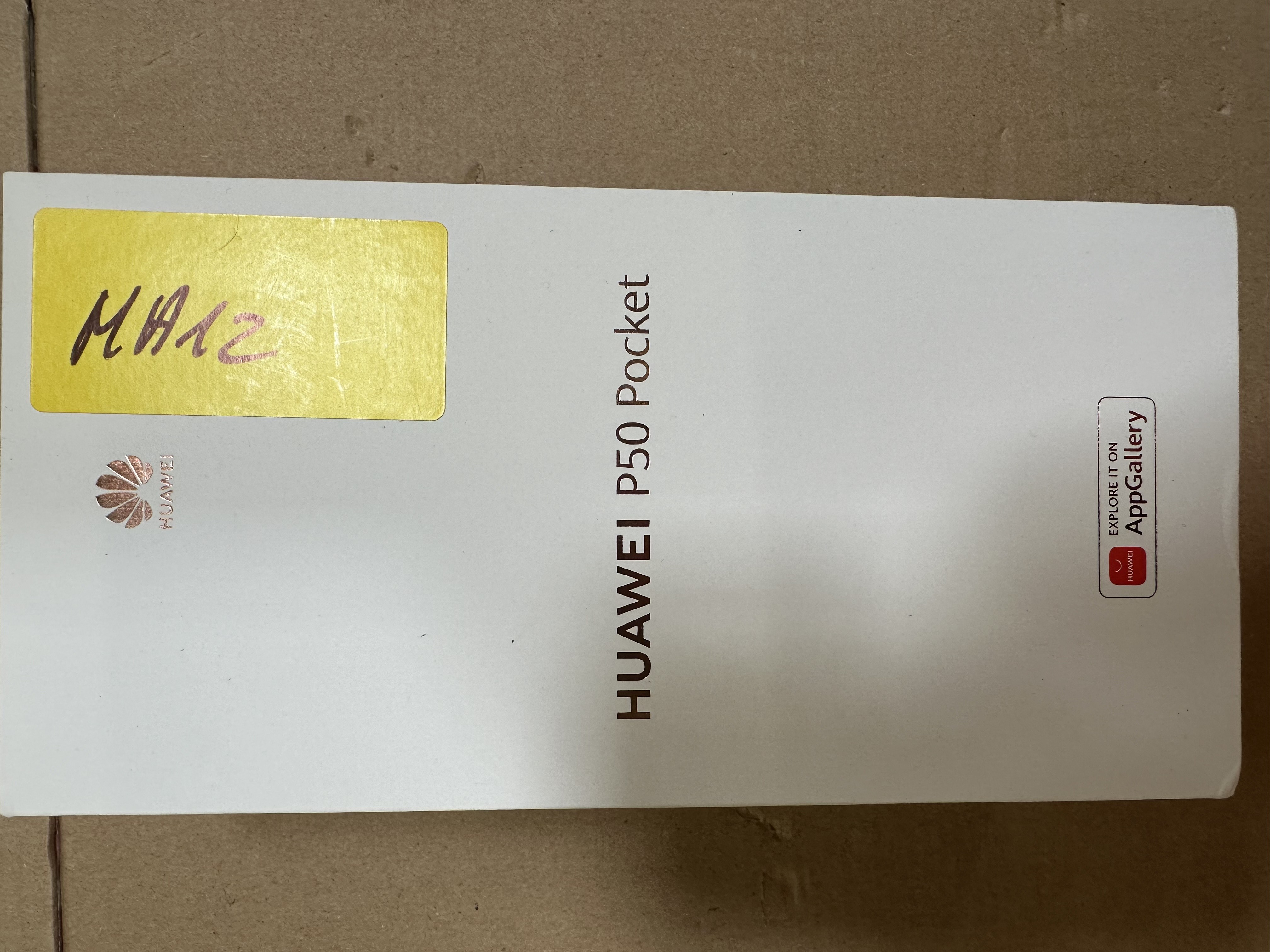 Białe pudełko Huawei P50 Pocket, żółta etykieta, nazwa telefonu z przodu.