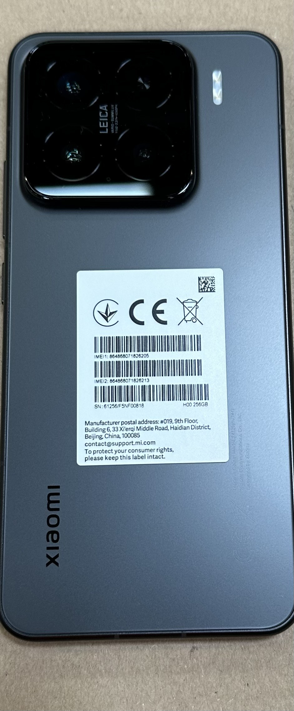 Tył szarego telefonu z wieloma obiektywami aparatu i etykietami informacyjnymi.