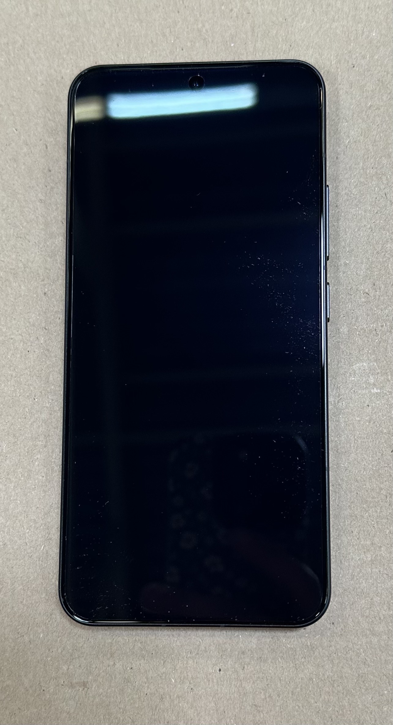 Czarny smartfon z wyświetlaczem i małym aparatem w górnej części środkowej.