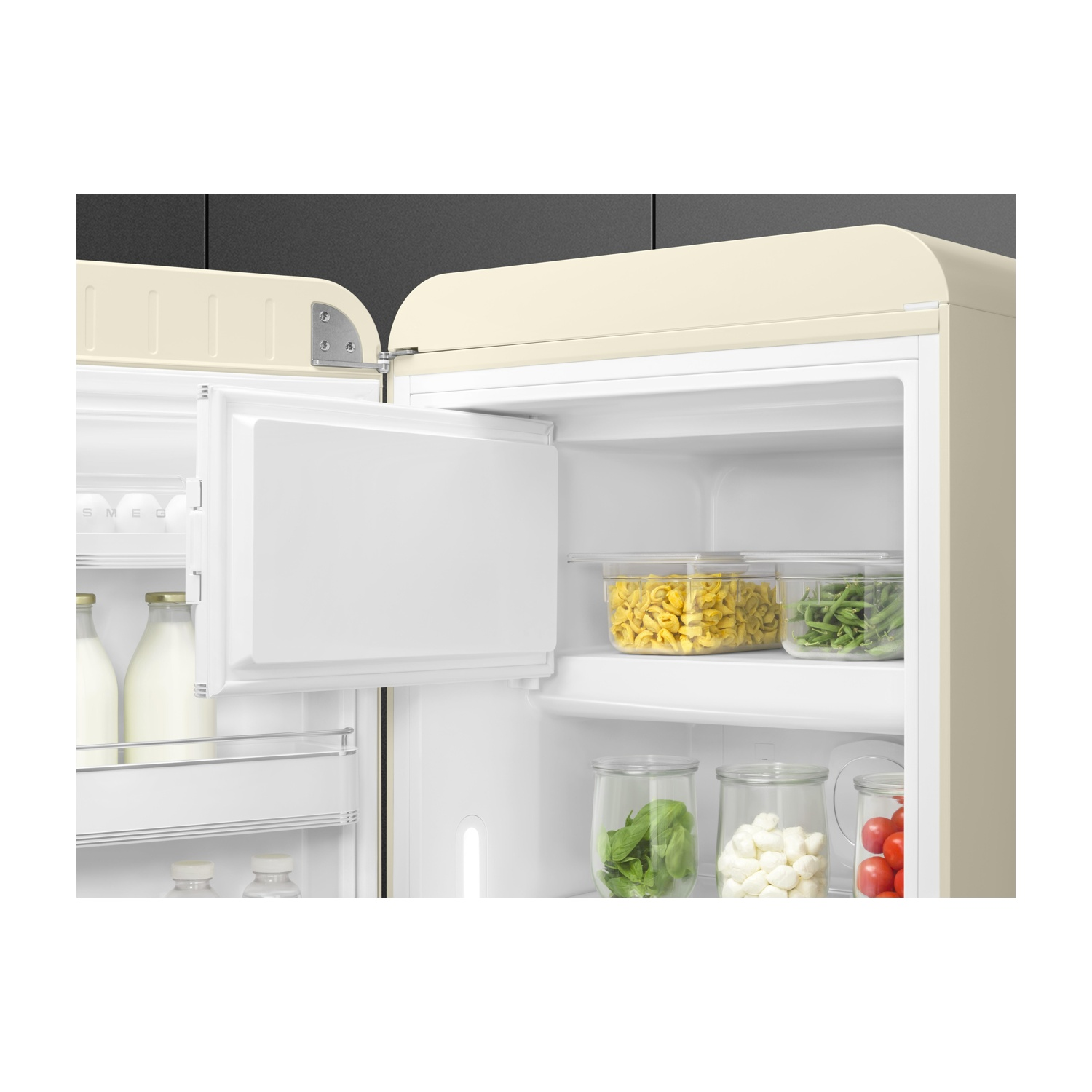 Frigorifero SMEG color crema aperto con pasta, fagiolini e altri alimenti all'interno.