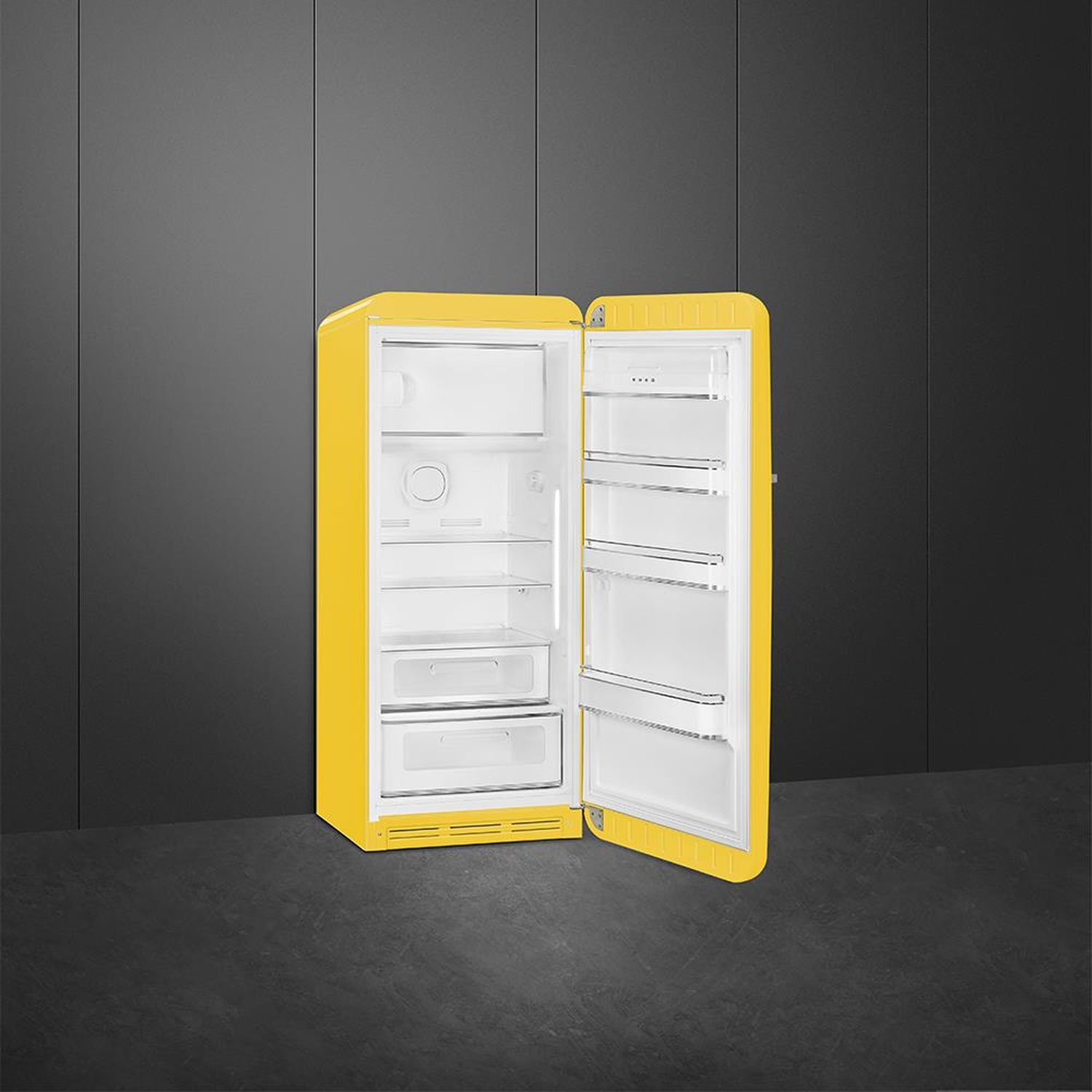 Frigorifero giallo con porta aperta. Interno bianco, ripiani, cassetti. Sfondo parete grigio scuro.