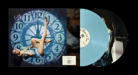 Vinyle et pochette d'album. Une femme allongée sur un cadran d'horloge. Pochette et disque visibles.