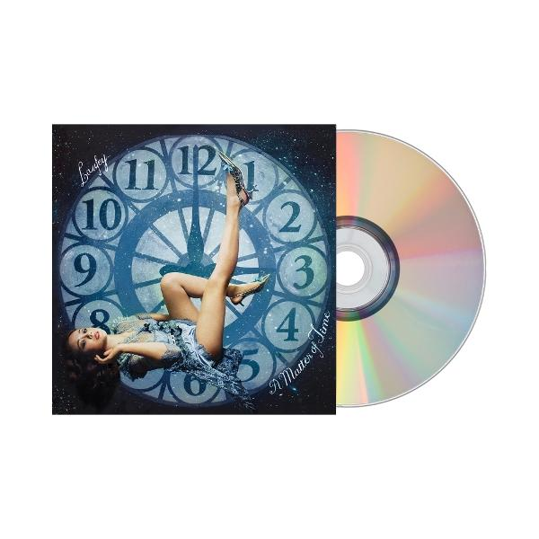 CD en albumhoes. Een vrouw ligt op een wijzerplaat.