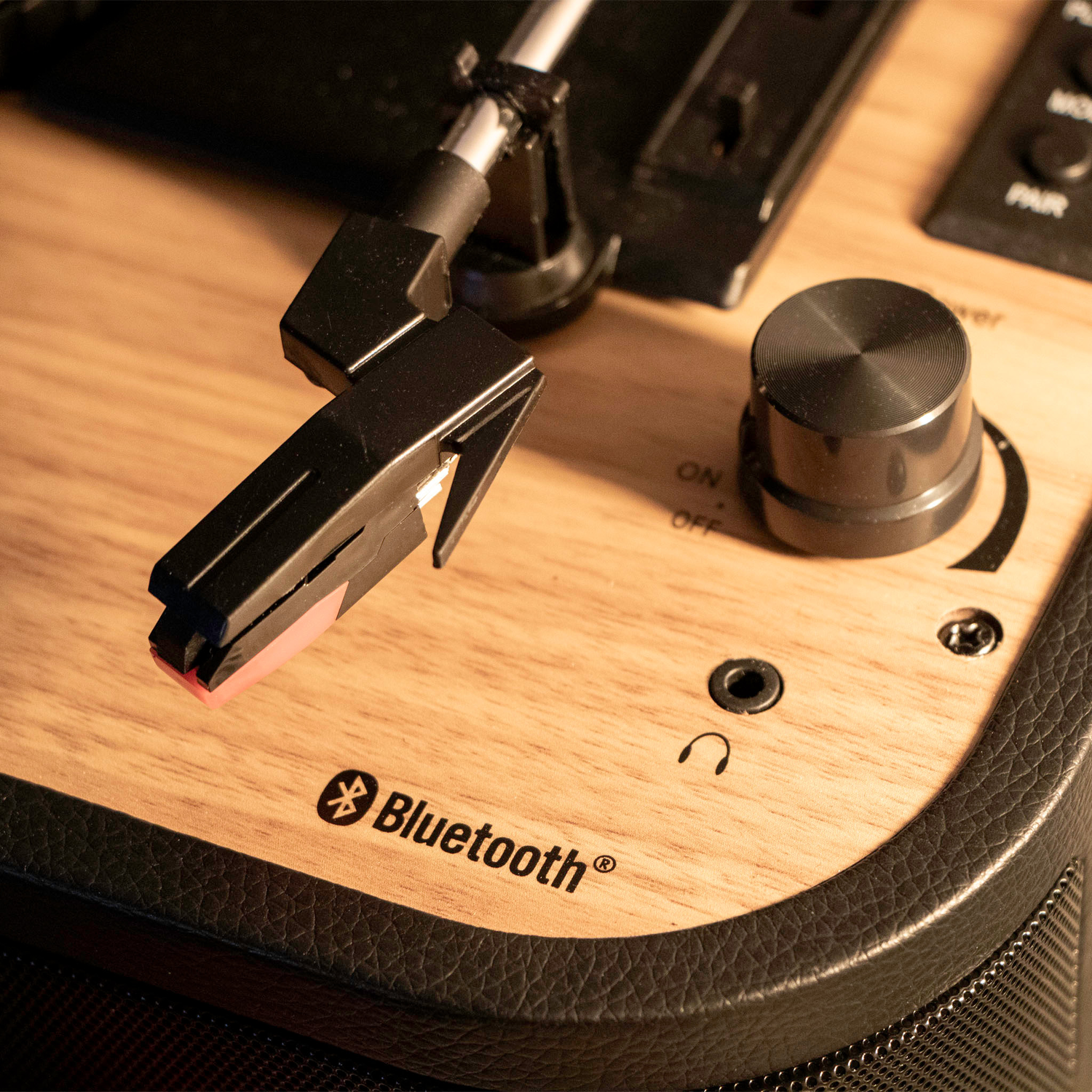 Een close-up van de naald, bedieningselementen en het Bluetooth-label van een platenspeler.
