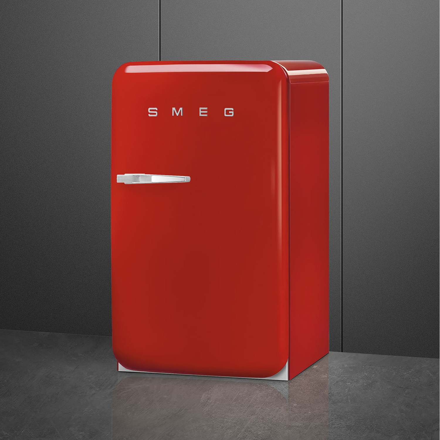 Frigorifero Smeg rosso contro un muro grigio scuro. La porta è chiusa.