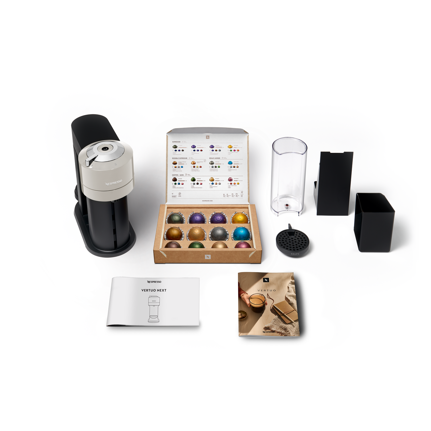 Nespresso machine with accessories, capsules and box on a white surface.