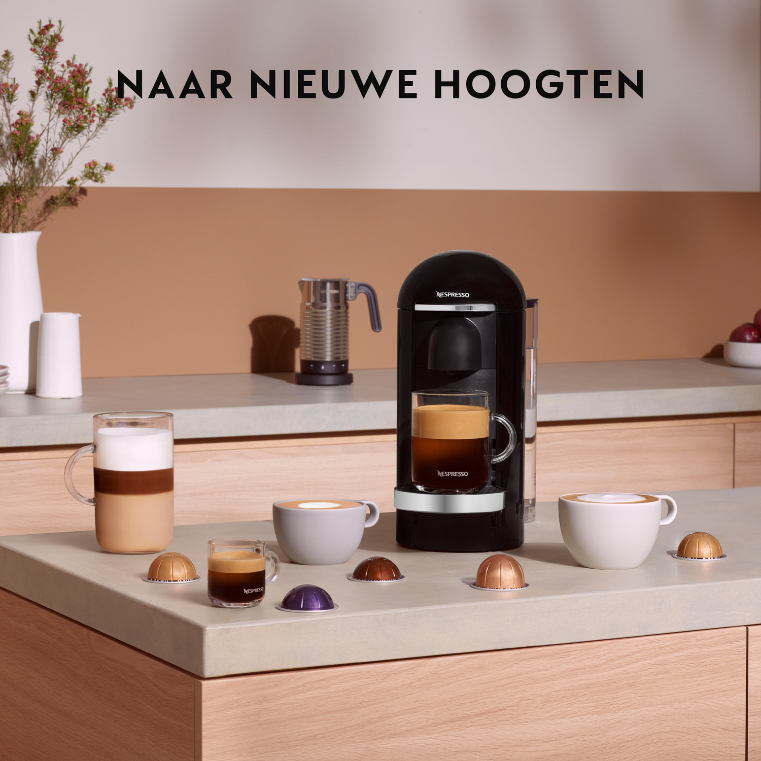 A kitchen counter with a coffee machine, cups of coffee, and capsules.