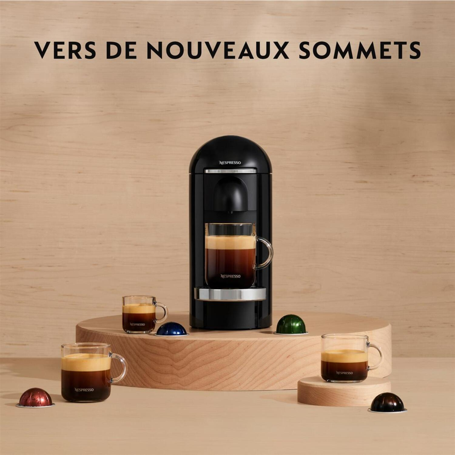 Machine Nespresso avec tasses de café et capsules sur une surface en bois.