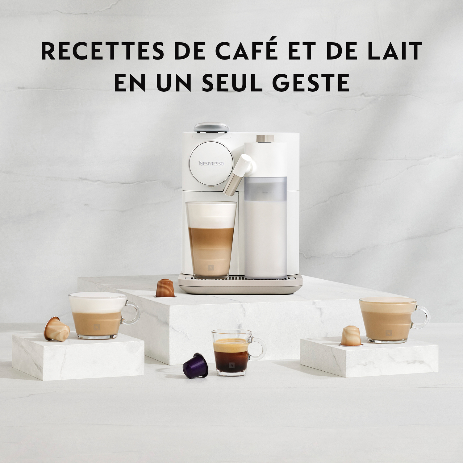 Machine à café blanche avec tasses à café sur des blocs de marbre et capsules.