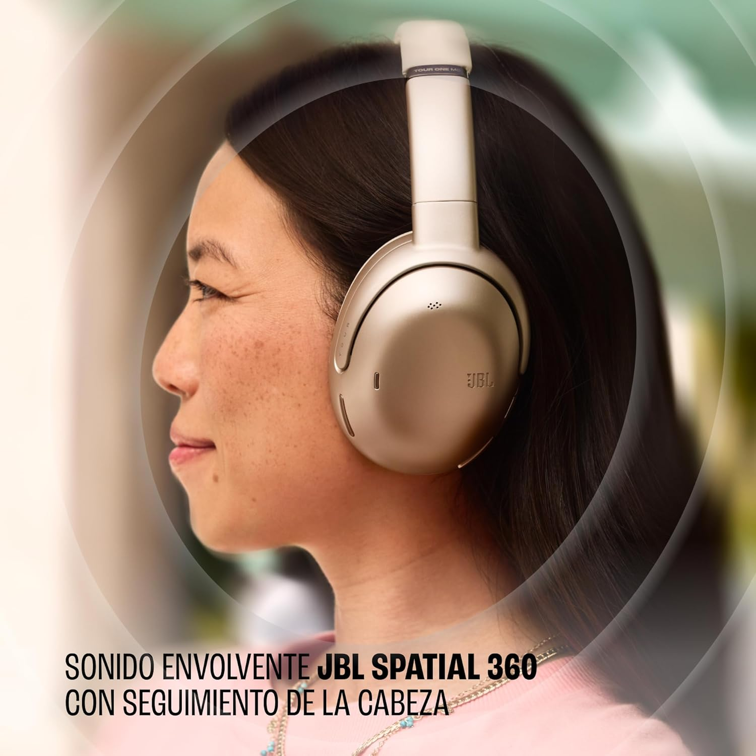 Una mujer con auriculares dorados, perfil, sonriendo.