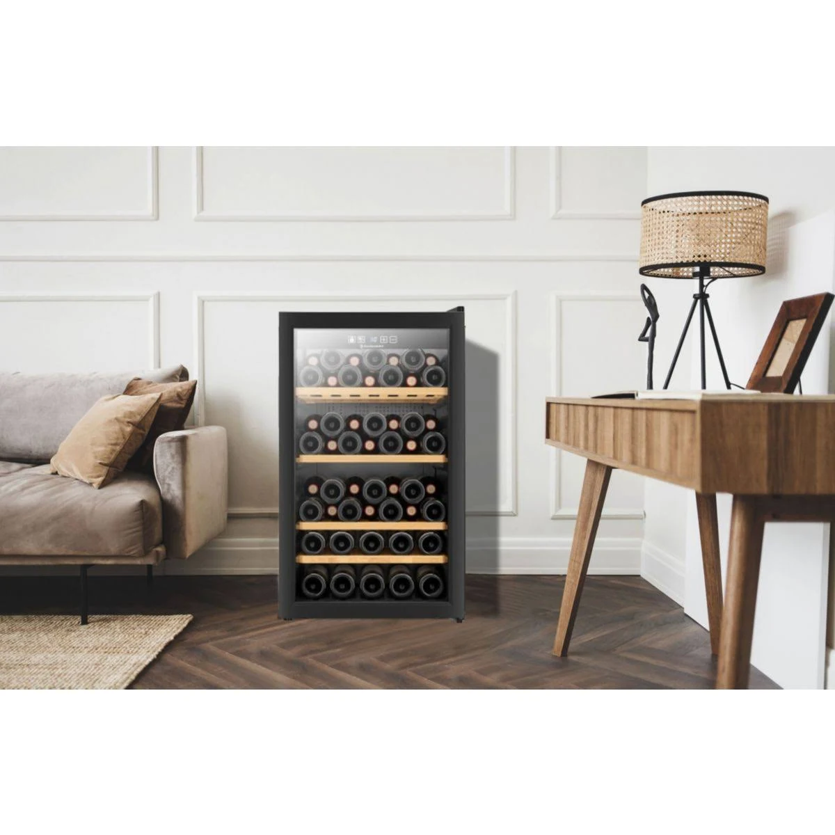 Refrigerador de vino con botellas. Habitación con alfombra, escritorio y lámpara a la derecha.