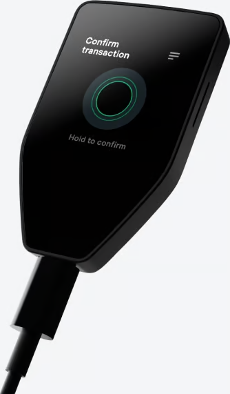 Appareil noir en forme de bouclier avec un écran affichant 'Confirmer la transaction' et un câble USB connecté.