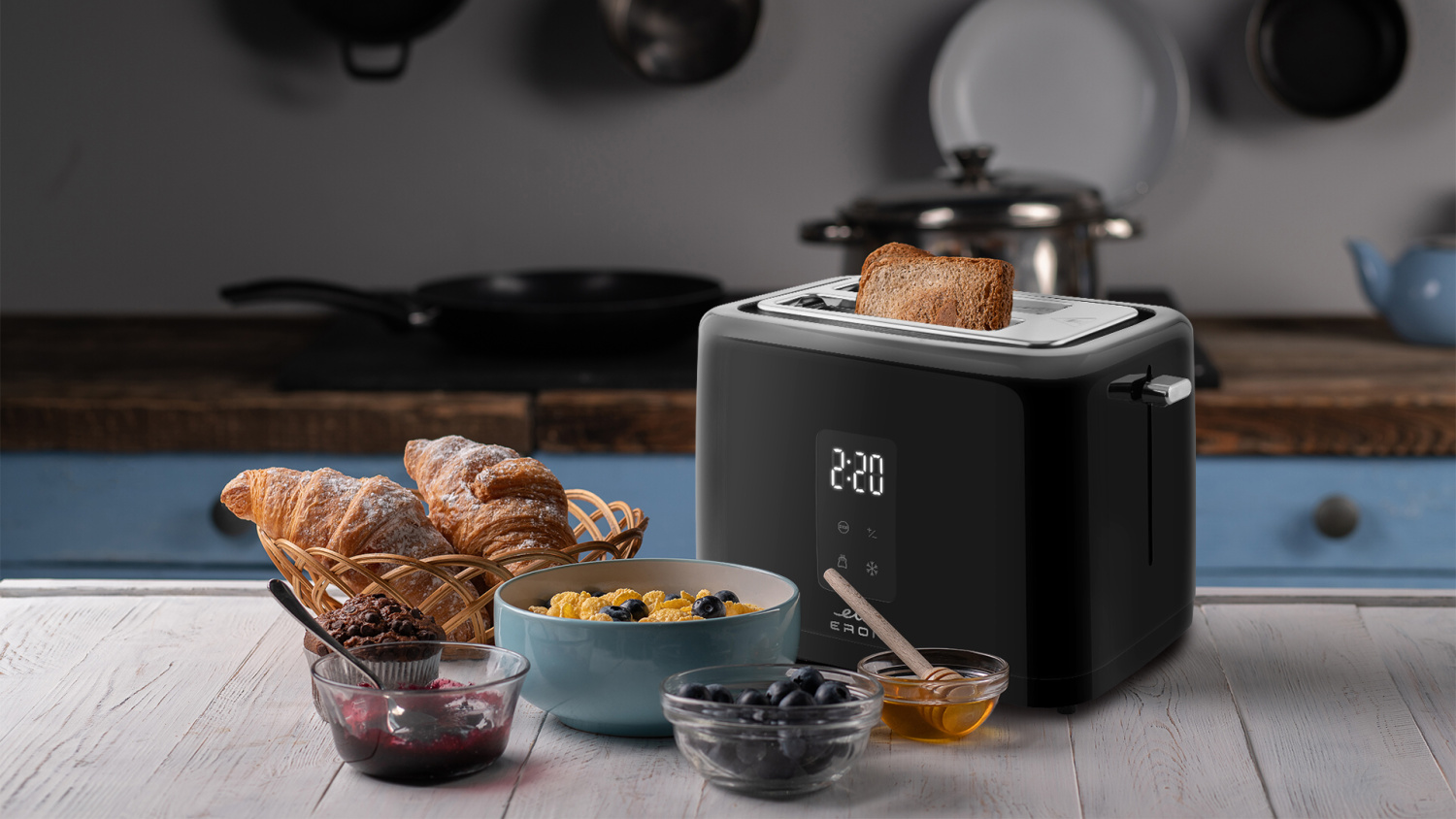 Reggeli jelenet kenyérpirítóval, pirítóssal, croissant-okkal és egyéb ételekkel az asztalon.