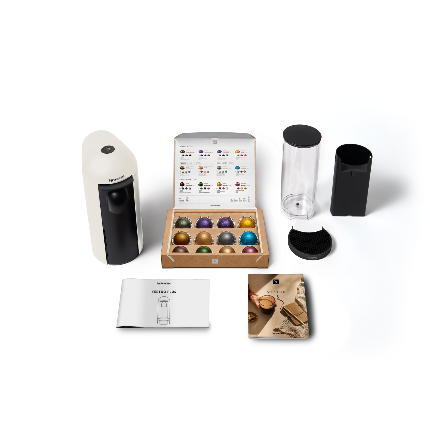 Coffee machine, capsules, and accessories arranged on a white surface.